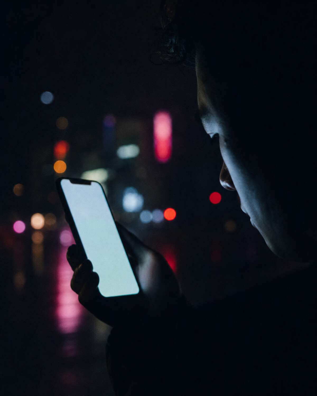 暗い室内でスマートフォンを見る人物
